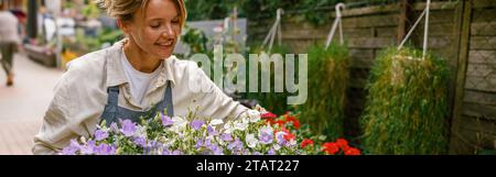 Professioneller Gärtner mit Schürze, der sich im Blumenladen um die Zimmerpflanze kümmert. Das Pflanzenpflegekonzept Stockfoto