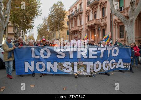 Messina, Italien. Dezember 2023. Demonstranten in Prozession mit MIMMO LUCANO (mit dem roten Hut, der 4. Von links) hinter dem Banner mit den Worten 'die Straße kann nicht berührt werden' während des Protestes gegen den Bau der Brücke über die Straße, organisiert von der No Bridge Coordination in Messina. Etwa zweitausend Menschen protestierten gegen den Bau der Brücke über die Meerenge von Messina, der längsten Hängebrücke der Welt in einem Gebiet, das heftigen Winden und starken Gezeitenströmen ausgesetzt ist, in einem der Gebiete mit dem höchsten Erdbebenrisiko im Mittelmeer. Hunderte von Stockfoto