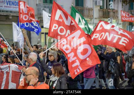 Messina, Italien. Dezember 2023. Marschierende Menschen schwingen Fahnen mit den Worten "keine Brücke" während des Protestes gegen den Bau der Brücke über die Straße, der von der Koordination "keine Brücke" in Messina organisiert wurde. Etwa zweitausend Menschen protestierten gegen den Bau der Brücke über die Meerenge von Messina, der längsten Hängebrücke der Welt in einem Gebiet, das heftigen Winden und starken Gezeitenströmen ausgesetzt ist, in einem der Gebiete mit dem höchsten Erdbebenrisiko im Mittelmeer. Hunderttausende von Quadratmetern Land, Häuser und öffentliche Unternehmen werden enteignet. Am Ende Stockfoto