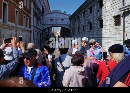 Touristen drängen sich für Fotos, an der Seufzerbrücke versuchen 3 Frauen in Venedig Segelkappen ein Gruppenfoto, einige halten Telefonkameras hoch, um die Aussicht einzufangen Stockfoto