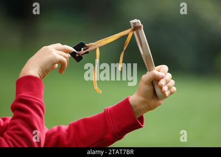 Kleiner Junge, der draußen mit Schleuder spielt, Nahaufnahme Stockfoto