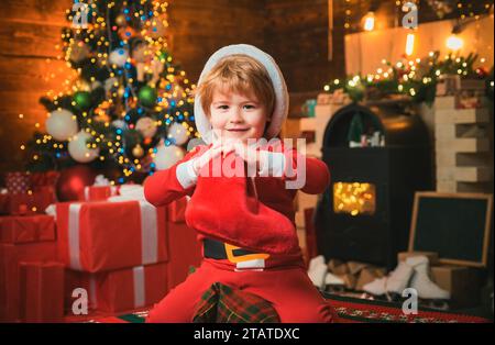 Weihnachtsstrumpfkonzept. Das fröhliche Gesicht des Kindes bekam ein Geschenk in einer weihnachtssocke. Überprüfen Sie den Inhalt des weihnachtsstrumpfs. Freude und Glück. Kindheitsmomente Stockfoto