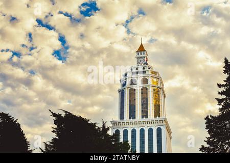 Batumi, Georgia - 15. november 2021: Turmarchitektur des Sheraton-Hotels mit alter Uhr auf der Spitze und vorbeiziehenden Wolken. Holi Stockfoto