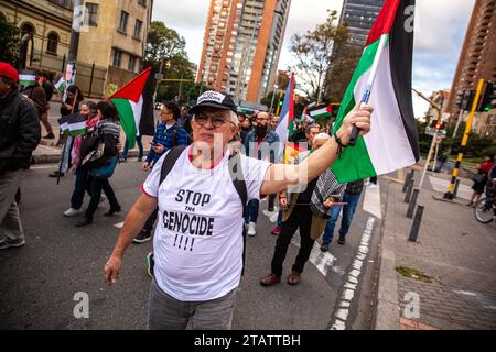 Ein Demonstrant, der ein T-Shirt trug, auf dem steht: "Stoppt den Völkermord", sah während der Demonstration eine Flagge schwenken. März in Bogotá zum Internationalen Tag der Solidarität mit dem palästinensischen Volk. (Foto: Antonio Cascio/SOPA Images/SIPA USA) Credit: SIPA USA/Alamy Live News Stockfoto