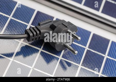 Auf den Solarpaneelen befindet sich ein Elektrostecker. Das Konzept der umweltfreundlichen Solarenergie. Stockfoto