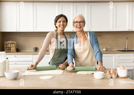 Fröhliche jüngere und ältere Bäckerinnen, die hausgemachte Backwaren kochen Stockfoto