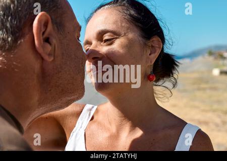 Nahaufnahme Porträt eines glücklichen Paares mittleren Alters, das romantische Momente am Strand genießt. Reifer Mann und Frau schauen sich gegenseitig in die Augen und berühren ihre Stockfoto