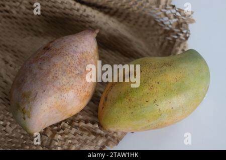 Frische große Totapuri-Mangos, saftig und lebendig in der Farbe. Er ist länglich und hat einen markanten Schnabel wie ein spitzes Ende Auf rustikalem Braun angeordnet Stockfoto