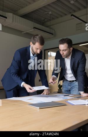 Zwei Geschäftsleute prüfen die in Diagrammen und Diagrammen dargestellten Vertriebsstatistiken Stockfoto
