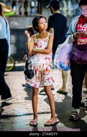 Ein hübsches, junges philippinisches Mädchen wartet auf ihre Familie vor der Kirche Santo Nino de Tondo in Manila auf den Philippinen. Stockfoto