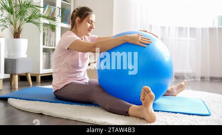 Schöne Frau in Sportbekleidung, die mit Fitball auf Teppich trainiert. Konzept von Gesundheit, Sport und Yoga zu Hause Stockfoto