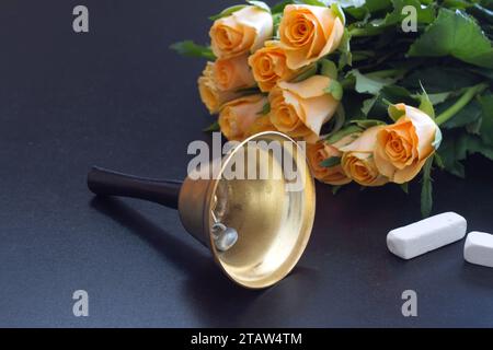 Glocke, Kreide und Rosenstrauß auf der Tafel, Konzept zurück zur Schule und Teacher Day Stockfoto