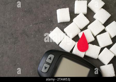 Zuckerwürfel mit rotem Bluttropfen und Glucometer, Diabeteskonzept Stockfoto