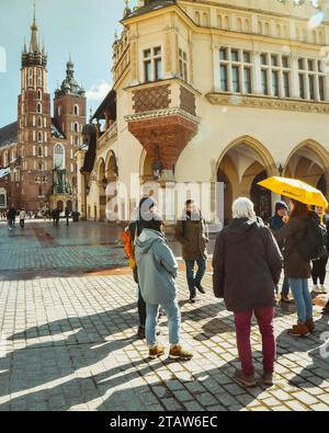 Krakau, Polen - 6. märz 2023: Reiseleiter mit Reisegruppe auf dem Hauptplatz in Krakau. Kostenlose Touristenwanderungen mit Einheimischen. Einzigartiges Erlebnis in New Cit Stockfoto