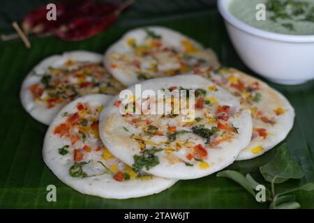 Uttapam auf Kochbananenblatt. Gesunder Pfannenkuchen aus fermentiertem Reis und Linsen. Garniert mit Zwiebeln, Karotten, Koriander und grünen Chilis. Ser Stockfoto