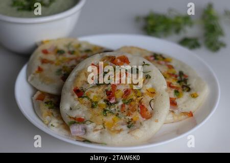 Südindisches Uttapam. Gesunder Pfannenkuchen aus fermentiertem Reis und Linsen. Garniert mit Zwiebeln, Karotten, Koriander und grünen Chilis. Serviert Stockfoto