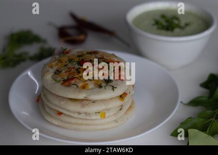 Südindisches Uttapam. Gesunder Pfannenkuchen aus fermentiertem Reis und Linsen. Garniert mit Zwiebeln, Karotten, Koriander und grünen Chilis. Serviert Stockfoto