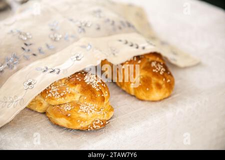 Challah-Brot mit Mohn und Sesamsamen. Mit weißer Abdeckung abgedeckt. Stockfoto