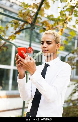 Wunderschöner junger Mann mit überraschtem Ausdruck mit der Nachricht auf dem Handy Stockfoto