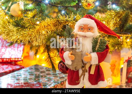 Weihnachtsmann-Figur und Geschenke unter dem Weihnachtsbaum. Stockfoto