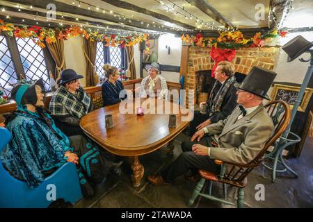 Dorking, Surrey, Großbritannien. Dezember 2023. Menschen in viktorianischer Kleidung im King Arms Pub, erwähnt im Roman Little Dorrit von Charles Dickens, in dem das Weihnachtsfest in Dorking Town Dickensian gefeiert wird. Quelle: Paul Quezada-Neiman/Alamy Live News Stockfoto