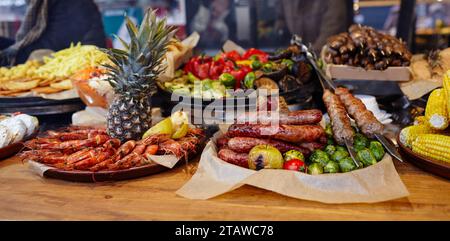 Weihnachtliches Street Food Festival auf Messe im Stadtzentrum, Winterferien. BBQ Street Food zum Verkauf, leckere Würstchen auf dem Holiday Street Market in europa Stockfoto