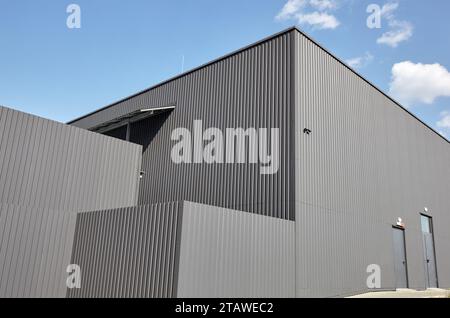 Gewelltes Stahllager oder Fabrikgebäude vor blauem Himmel. Architektur. Metallstruktur Stockfoto