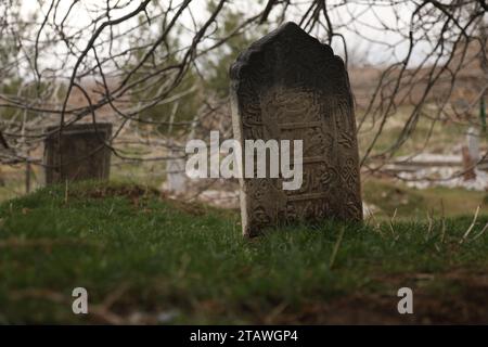 Friedhof in grüner Umgebung, mit einem arabischen Satz auf dem Grab | Foto eines islamischen Grabes. Stockfoto