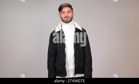 Ein hübscher junger Mann, der glücklich vor grauem Hintergrund steht. Stockfoto