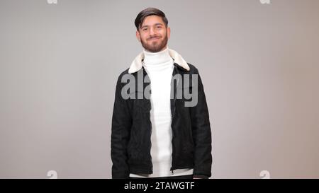 Ein hübscher junger Mann, der glücklich vor grauem Hintergrund steht. Stockfoto