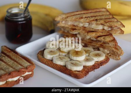 Üppiges Honig-Bananenbrot-Sandwich, goldene Brotschichten mit frisch geschnittenen Bananen, mit süßem Honig getränkt, köstliches Frühstückskonzept Stockfoto