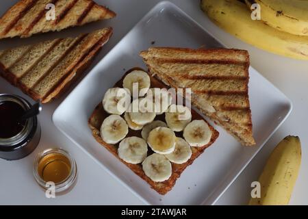 Üppiges Honig-Bananenbrot-Sandwich, goldene Brotschichten mit frisch geschnittenen Bananen, mit süßem Honig getränkt, köstliches Frühstückskonzept Stockfoto