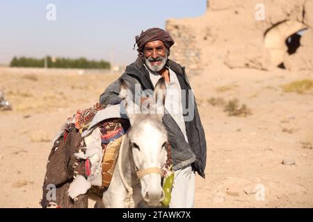 Ein alter Mann, der auf einem weißen Esel reitet, glücklich damit spielt und den Moment mit einem Lächeln genießt. Kabul, Afghanistan Stockfoto