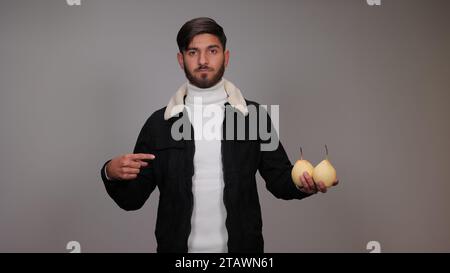 Ein junger Mann, der Birnen hält und die Menschen ermutigt, Birnen zu essen. Stockfoto