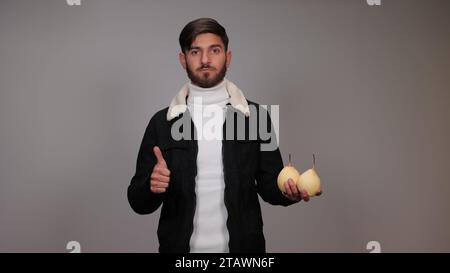 Ein junger Mann, der Birnen hält und die Menschen ermutigt, Birnen zu essen. Stockfoto