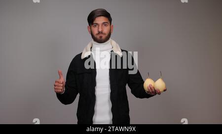 Ein junger Mann, der Birnen hält und die Menschen ermutigt, Birnen zu essen. Stockfoto