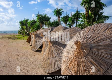 Reed, Strohschirm, Bambus, Schilf, Strohschirm am Strand. Ein Hut, ein Strohschirm, entfernt und auf seinem Standfuß liegend, steht mir Stockfoto