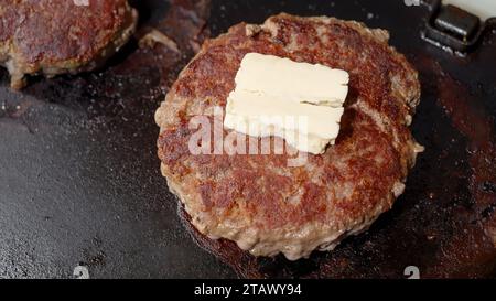 Blick von oben auf die Butter, die auf Rindfleischburgern im elektrischen Grill schmilzt. Kochen zu Hause, Küchengerät, gesunde Ernährung, Hamburger Zutaten Stockfoto