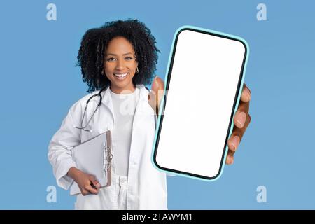 Afroamerikanerin zeigt Smartphone mit leerem Bildschirm, Studio Stockfoto