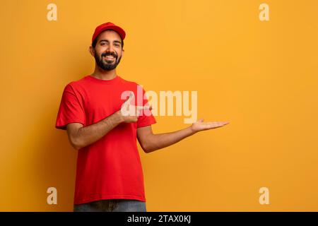 Indischer Liefermann in Uniform lächelt und zeigt auf seine offene Palme Stockfoto