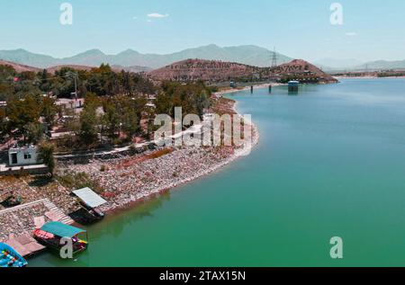 Ein Fluss, der durch ein grünes Dorf und Berge in Afghanistan fließt Stockfoto