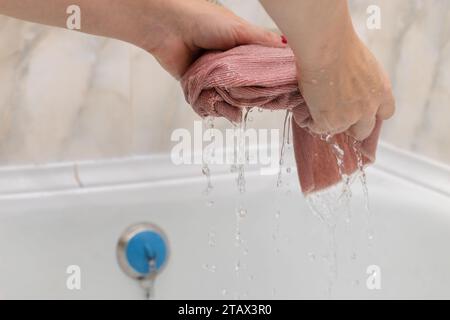 Weibliche Hände wringen einen nassen Lappen aus. Frau, die einen Lappen wäscht. Nassreinigung. Stockfoto