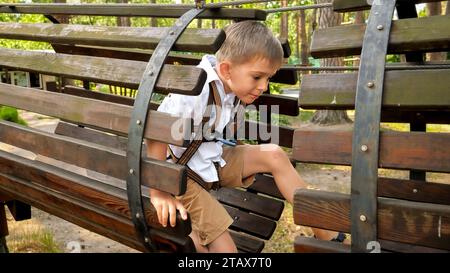 Kleiner Junge, der durch Holzrohr oder Tunnel auf dem Spielplatz im Park kriecht. Aktive Kindheit, gesunder Lebensstil, Kinder, die draußen spielen, Kinder in Natur Stockfoto