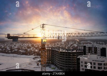 Industriekräne auf der Baustelle mit dramatischem Sonnenuntergang-Himmel-Hintergrund. Stockfoto