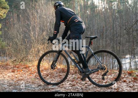 Profi-Radfahrer in Sportbekleidung und Helm fahren auf einer Strecke im Herbstwald. Stockfoto