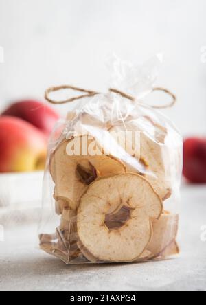 Getrocknete Apfelringe aus biologischem Anbau in durchsichtiger Verpackung und rote reife Äpfel in Box. Stockfoto