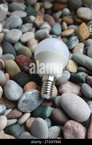 Energiesparlampe auf Einem farbigen Hintergrund mit glatter Kieselstruktur Stockfoto