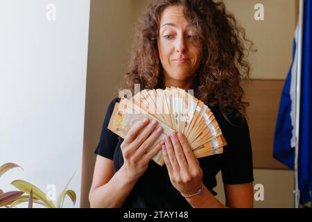 Eine Frau beobachtet das Geld, das sie in beiden Händen hält Stockfoto