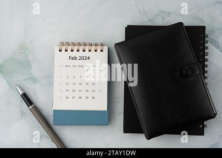 Februar-Kalender 2024, Stift und persönlicher Organizer auf Marmorschreibtisch flach gelegt Stockfoto