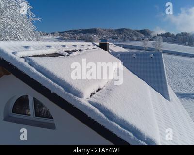 Schneebesen decken Solarpaneele auf einem Hausdach im Winter. Trotz der kühlen Umgebung sind die Photovoltaik-Panels widerstandsfähig. Perfekt für Illustratoren Stockfoto